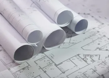 Rolled-up and unrolled architectural blueprints on a flat surface.