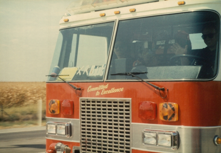 A red fire truck with "Committed to Excellence" written on the front, driving on a road.