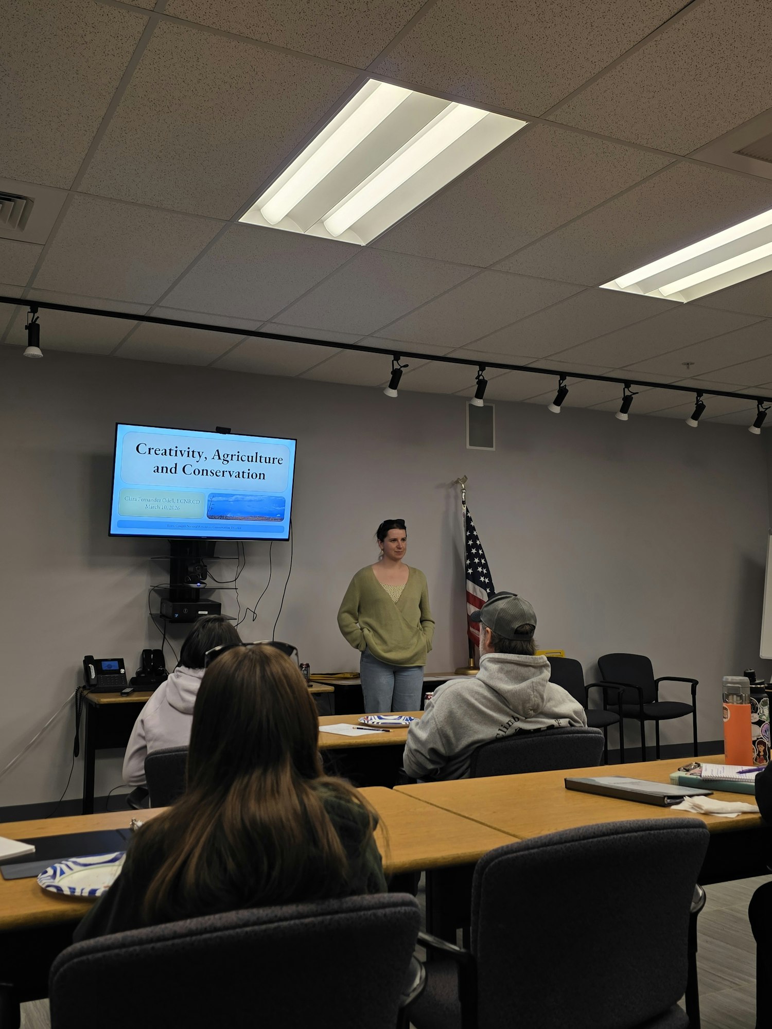 A presentation on "Creativity, Agriculture, and Conservation" is being given, with students seated and a projector screen displayed.