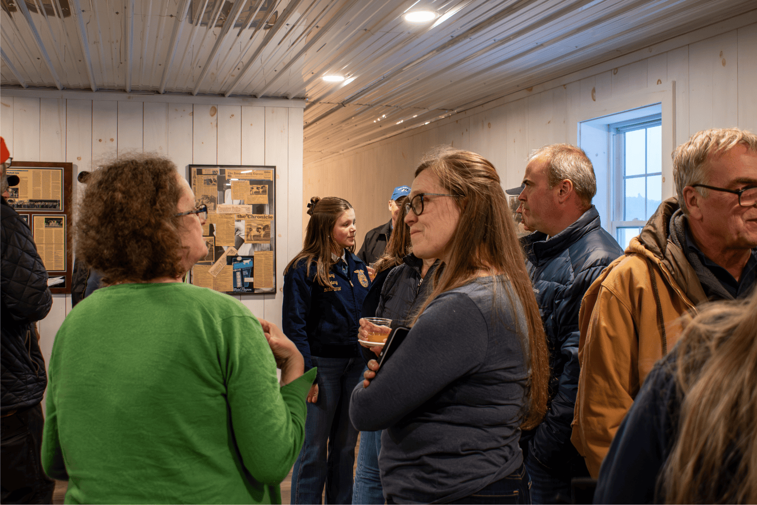 A group of people engaged in conversation in a room with informational displays on the walls.