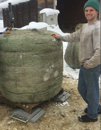 Dan Webster smiling, next to a large wrapped hay bale on OCNRCDs portable scales.