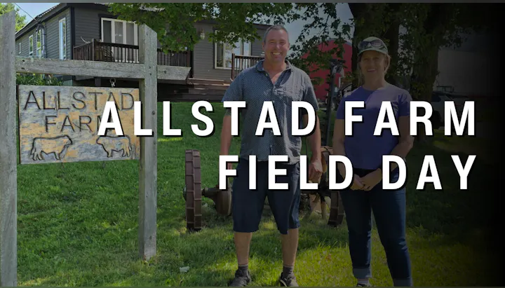 A sign for Allstad Farm announces a Field Day, featuring two smiling individuals in front of the farm.