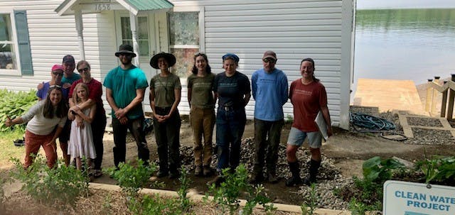 group of people standing near a lake shoreland restoration project recently installed