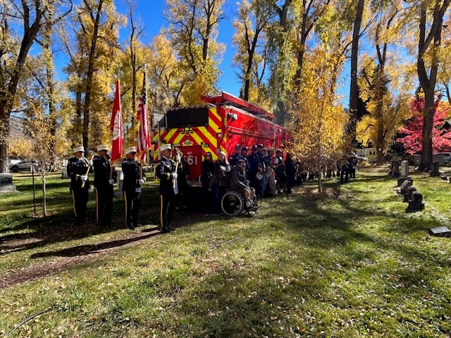 Upside-down image of a firetruck and trees reflected in water. Flip it for the correct view.