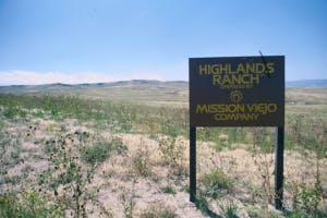 A sign for "Highlands Ranch" by Mission Viejo Company, set against a grassy landscape and clear blue sky.