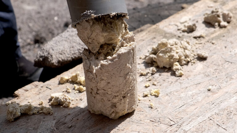 A core sample being extracted from the ground, showing layers of soil or sediment.