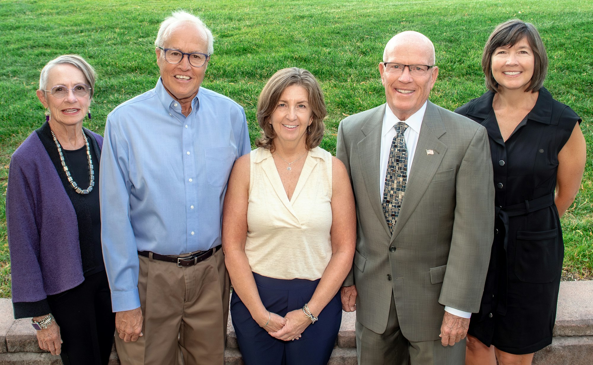 The five members of the Highlands Ranch Water board of directors posing together outdoors, smiling, with green grass in the background.