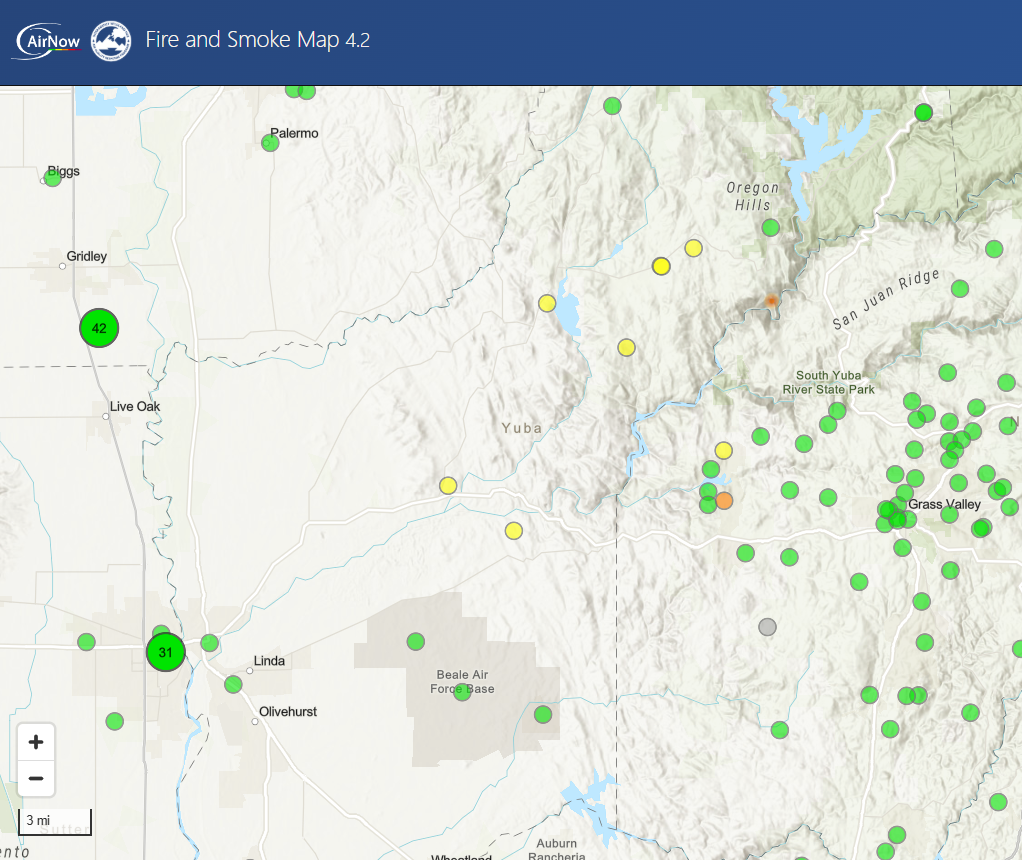 The image shows a fire and smoke map highlighting air quality monitoring stations, marked by color-coded dots across the area.