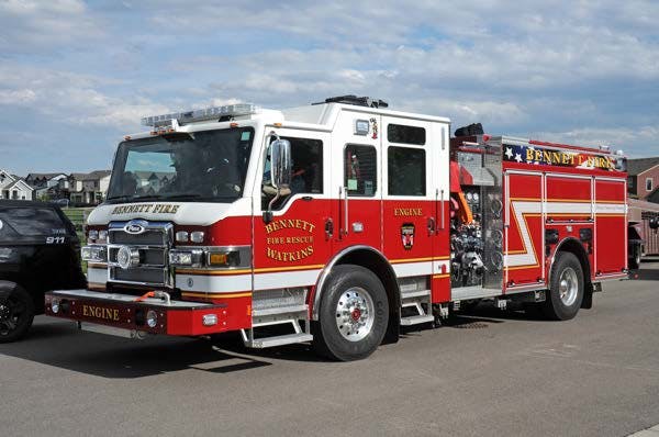 Red and white fire truck parked on the street, clear sky background.