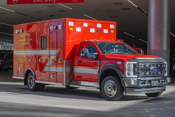 A red fire department ambulance with "Bennett Fire Protection District" on the side, parked in a covered area.