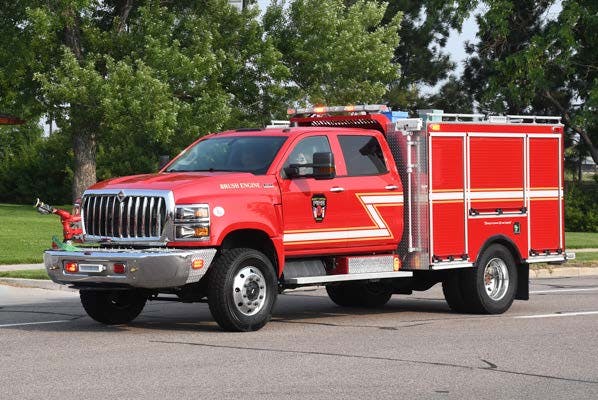 A red fire truck parked on the road, surrounded by trees.