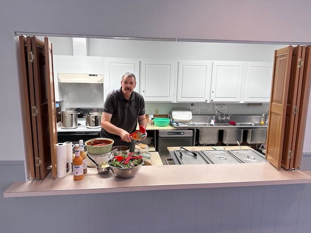 A man cooking in a kitchen with pots, ingredients, and utensils.