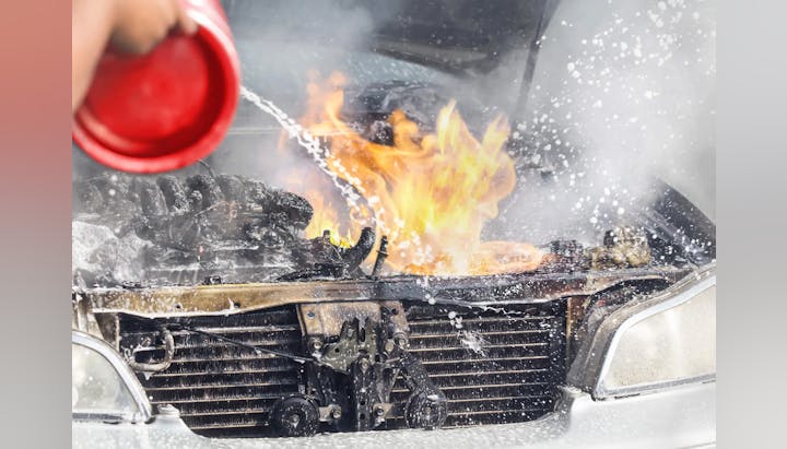 A car engine on fire being extinguished.