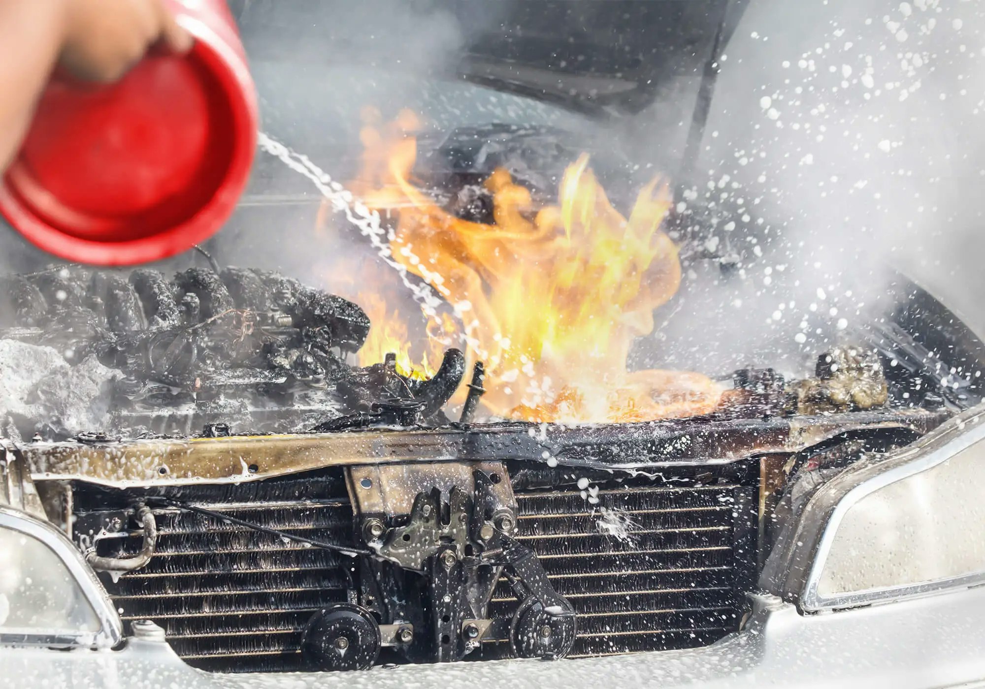 A car engine on fire being extinguished.