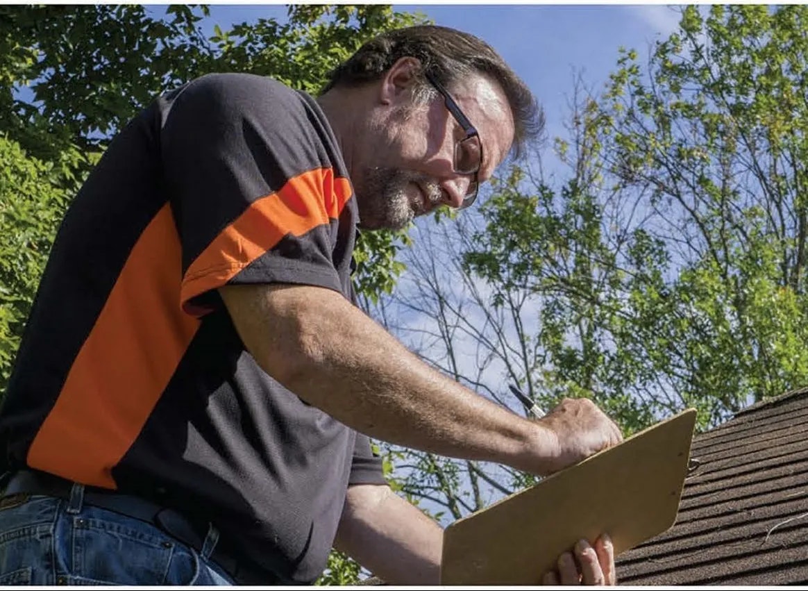 A person working on a roof with trees in the background.