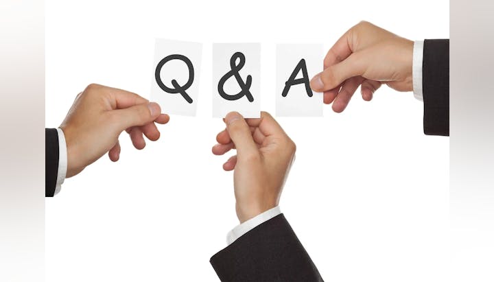 Two hands holding up cards that form the acronym "Q&A," symbolizing questions and answers.