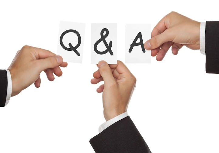 Two hands holding up cards that form the acronym "Q&A," symbolizing questions and answers.