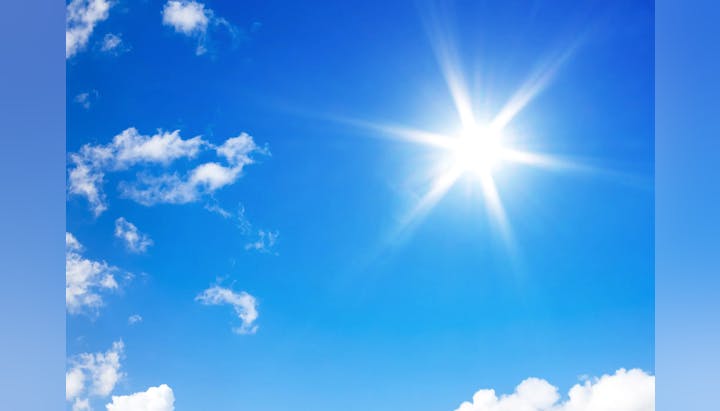 Bright sun with rays and blue sky with scattered clouds.