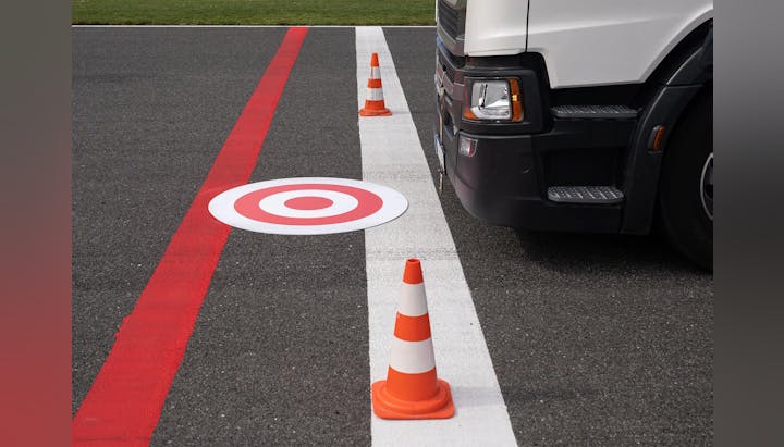 Truck at a checkpoint with traffic cones and a target sign on the ground.