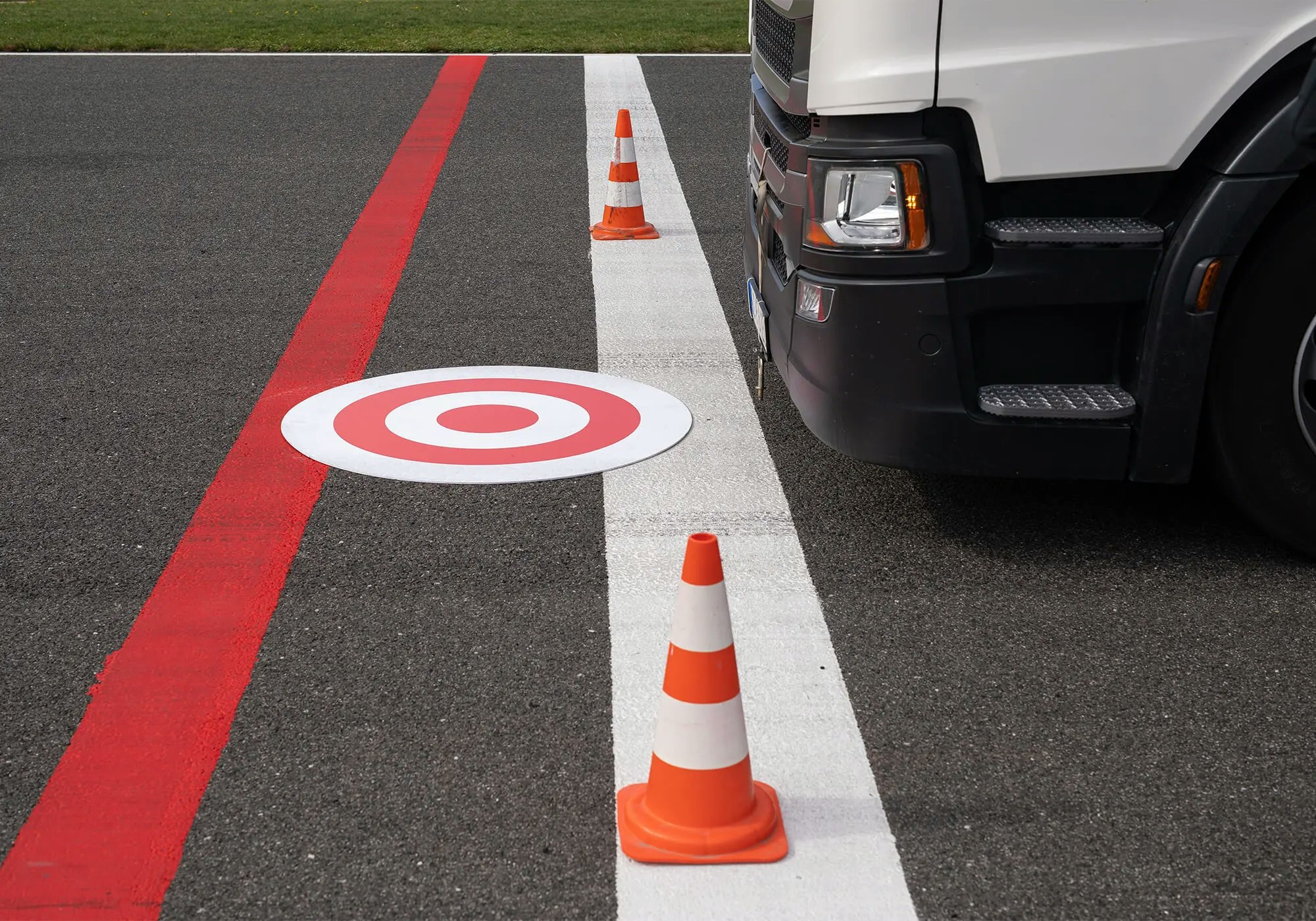 Truck at a checkpoint with traffic cones and a target sign on the ground.