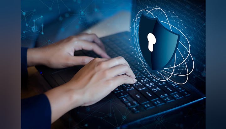 Hands typing on a laptop with a digital overlay of a shield and network connections, symbolizing cybersecurity.