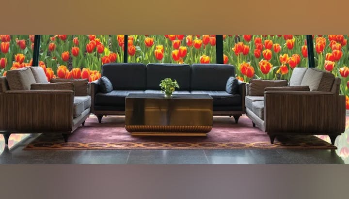 Modern lounge area with a sofa, armchairs, a coffee table, and a vibrant tulip wall mural.
