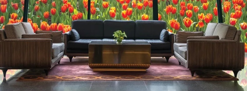Modern lounge area with a sofa, armchairs, a coffee table, and a vibrant tulip wall mural.
