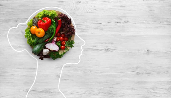 Outline of a head filled with vegetables on a wood background, symbolizing healthy eating or brain food.