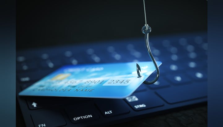 The image shows a credit card caught on a fishing hook, implying a theme of online fraud or phishing.
