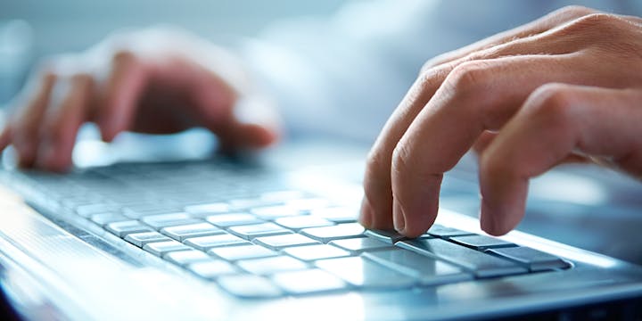 Hands typing on a laptop keyboard.
