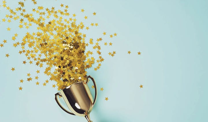 Golden trophy with star-shaped confetti on a blue background.