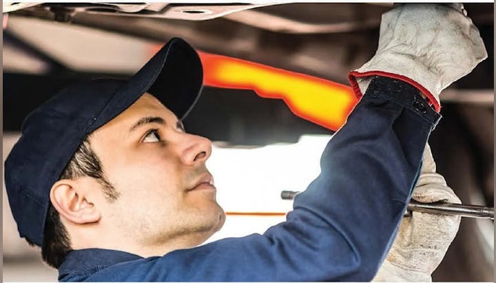 A mechanic is working under a vehicle, inspecting or fixing something.
