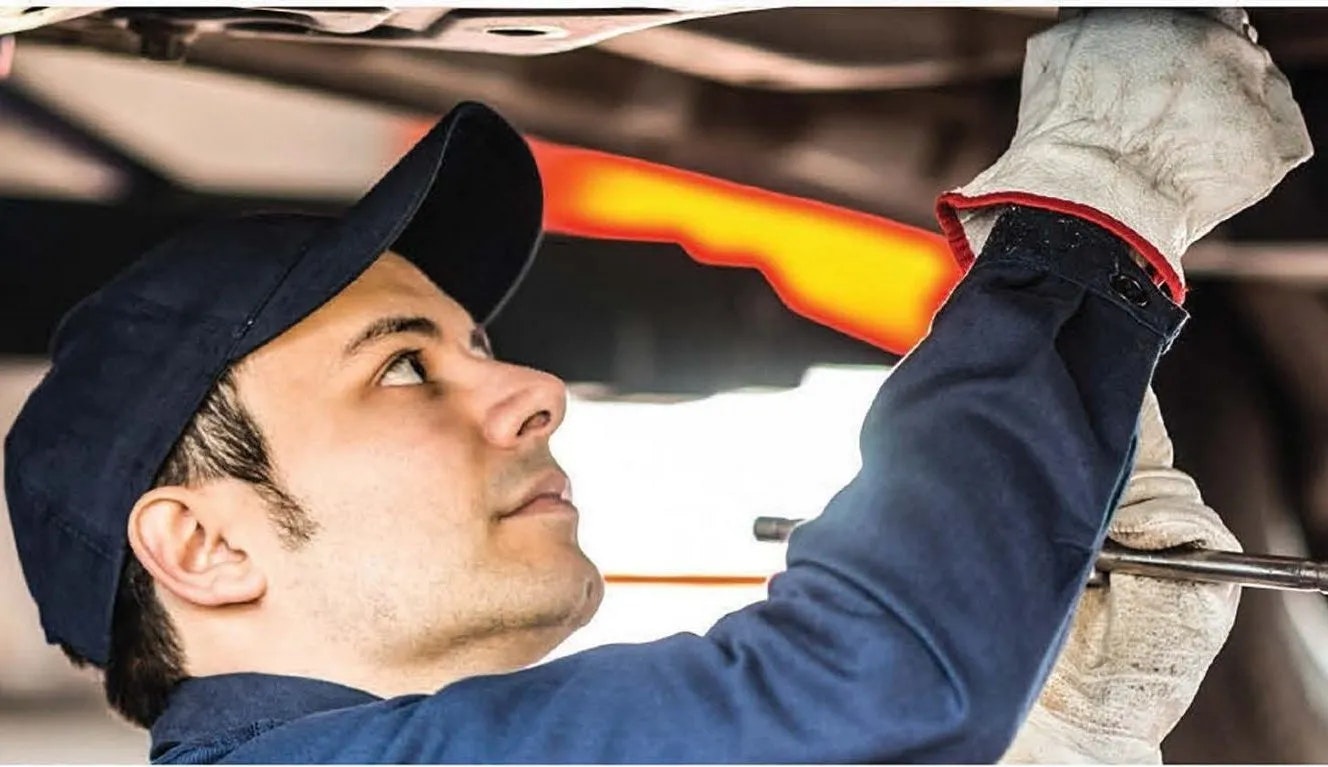 A mechanic is working under a vehicle, inspecting or fixing something.