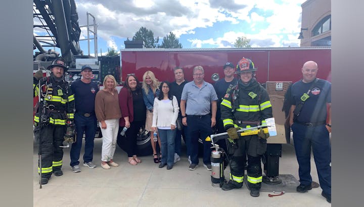 Group of people posing with firefighters in front of a fire truck.