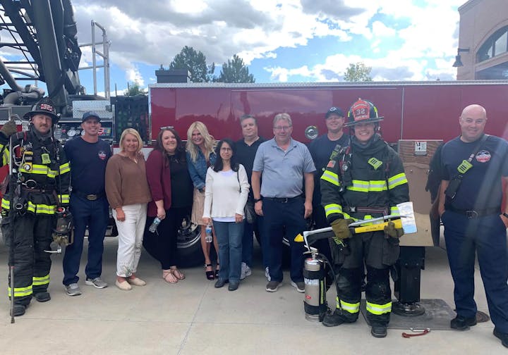 Group of people posing with firefighters in front of a fire truck.