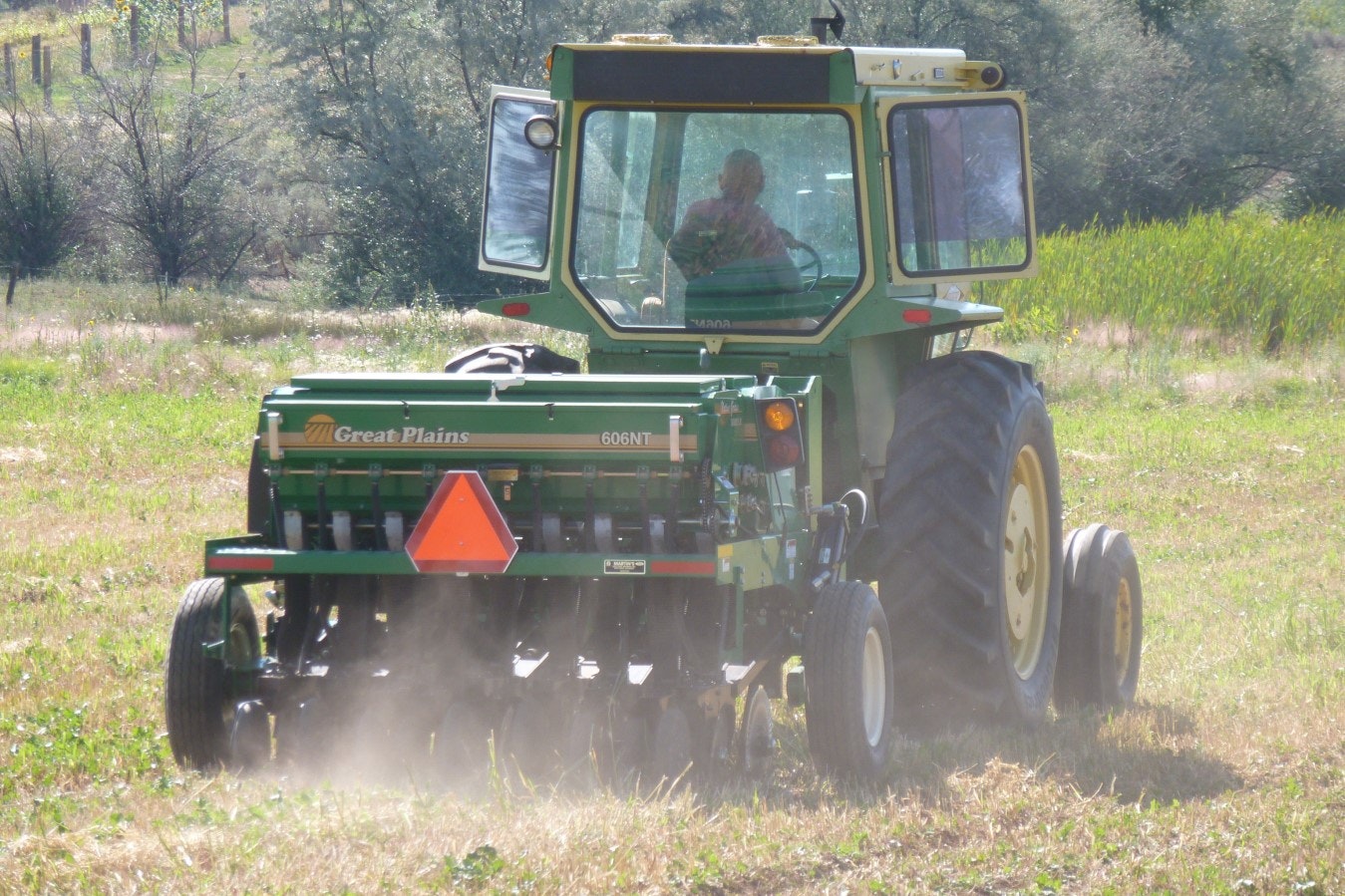 A tractor with a seeding attachment working in a field.