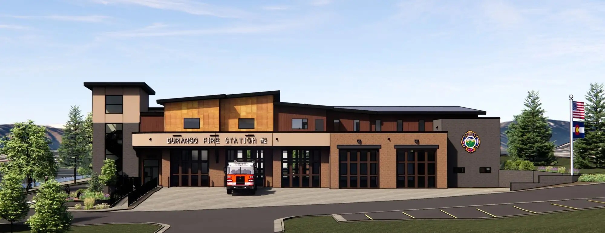 A modern fire station with an emergency vehicle, flags, and trees.