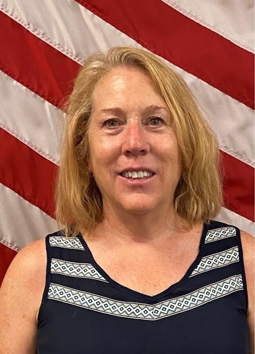 A smiling woman in front of the American flag.