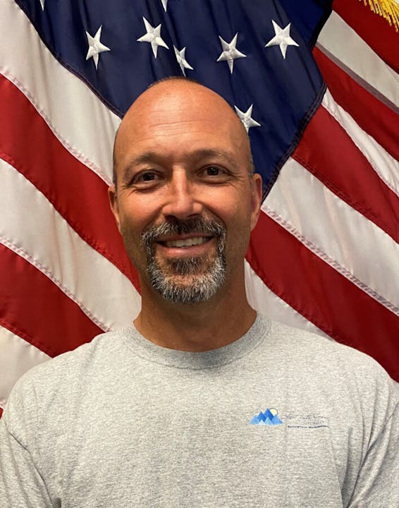 A smiling man in front of an American flag.