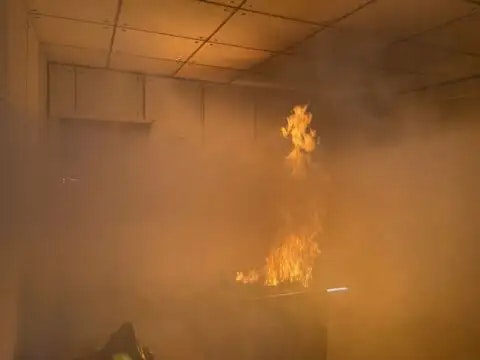 An indoor fire with smoke, flames licking the ceiling from below.