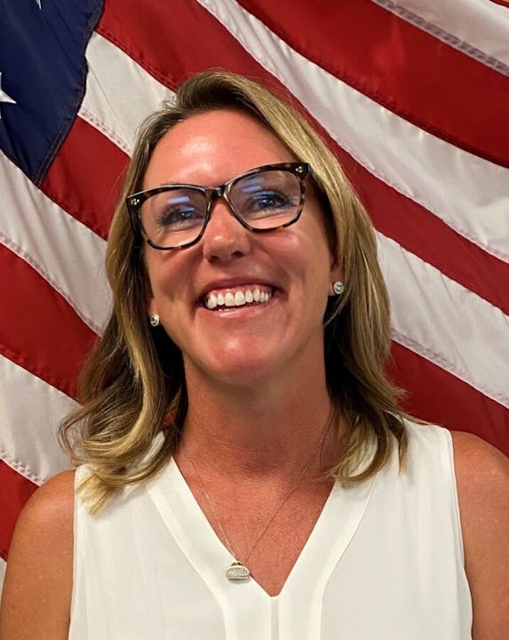 Smiling woman in front of an American flag.