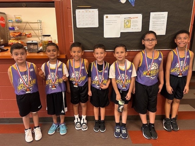 A group of young basketball players posing with medals.