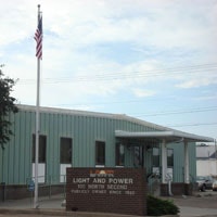 A building with a sign "Light and Power," American flag, clear sky.