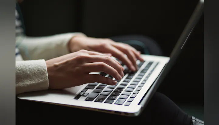 A close-up of hands typing on a laptop keyboard, highlighting the act of working or engaging with technology.