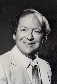 May contain: face, head, person, photography, portrait, formal wear, happy, smile, clothing, suit, accessories, tie, coat, and shirt