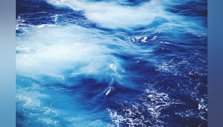 The image features swirling ocean waves with various shades of blue and hints of white foam.