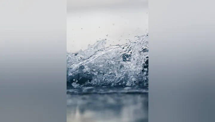 The image features dynamic splashes of water, capturing droplets and waves against a blurred background.