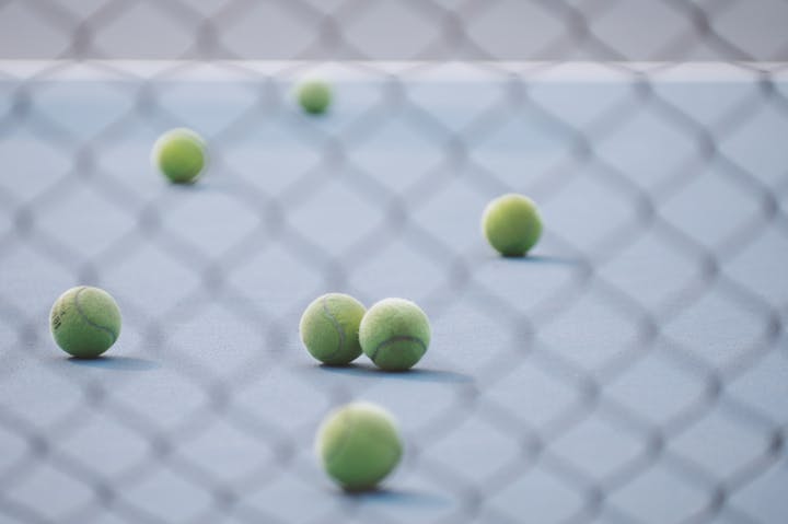 Tennis balls on a court with shadow of a net.
