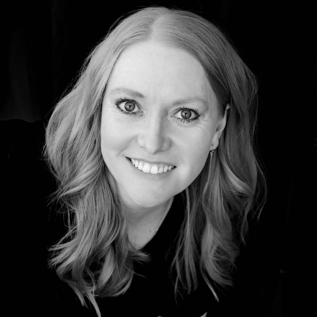 A black and white portrait of a smiling woman with long hair.