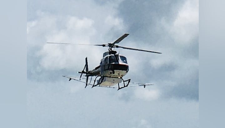 A helicopter flying against a cloudy sky.